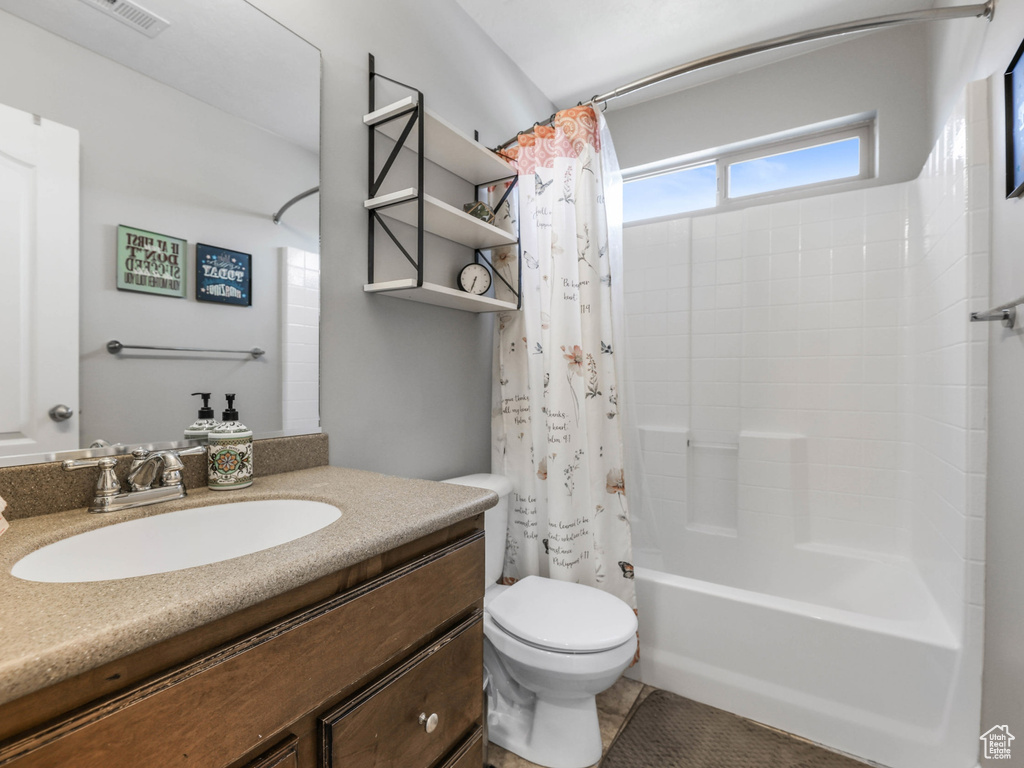Bathroom featuring toilet, shower / bathtub combination with curtain, and vanity