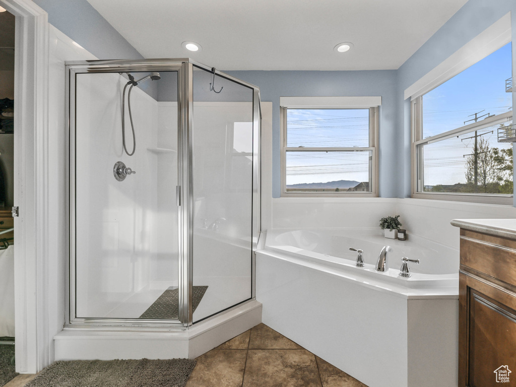 Bathroom with a stall shower, a garden tub, vanity, tile patterned floors, and recessed lighting