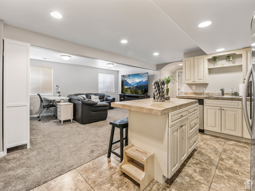 Kitchen with light colored carpet, cream cabinetry, stainless steel refrigerator, open floor plan, and recessed lighting