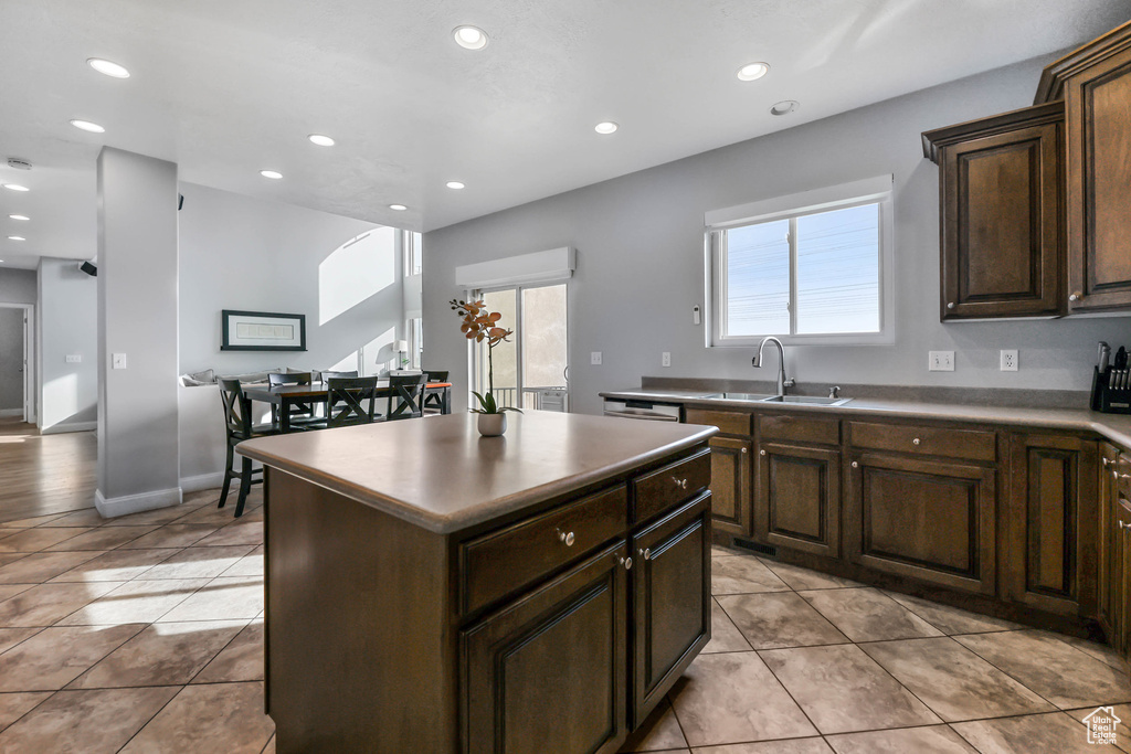 Kitchen with a sink, light tile patterned flooring, a center island, recessed lighting, and dark brown cabinets