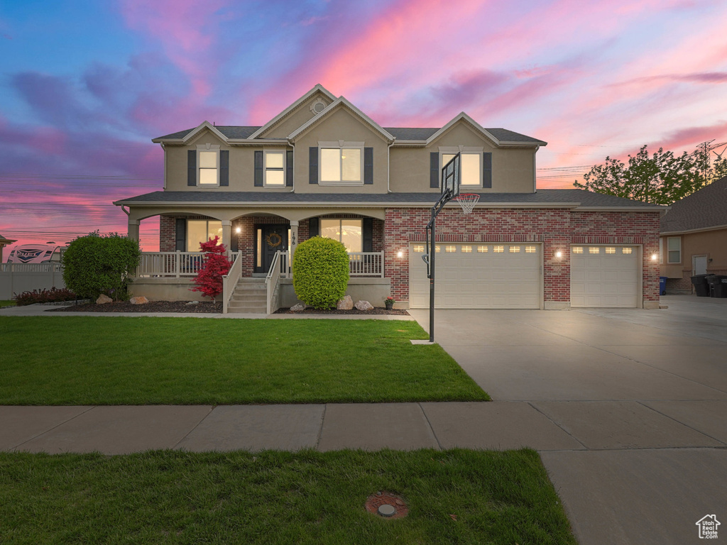 Traditional-style home featuring concrete driveway, a porch, a lawn, brick siding, and an attached garage