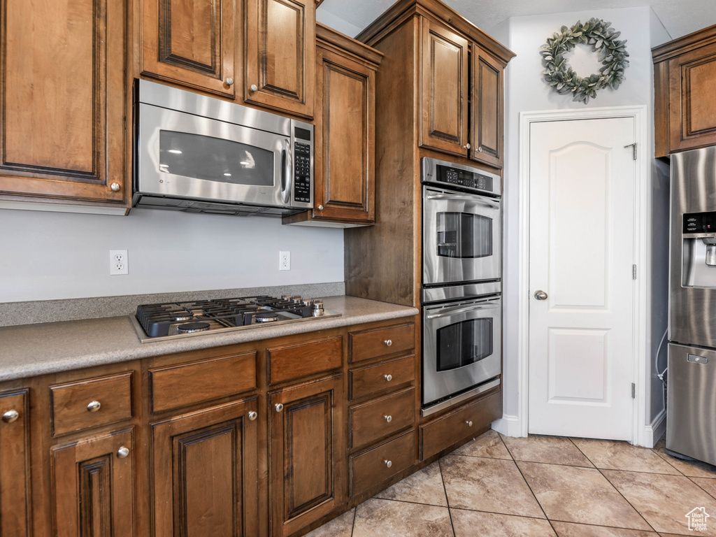 Kitchen with stainless steel appliances, light tile patterned floors, and light countertops