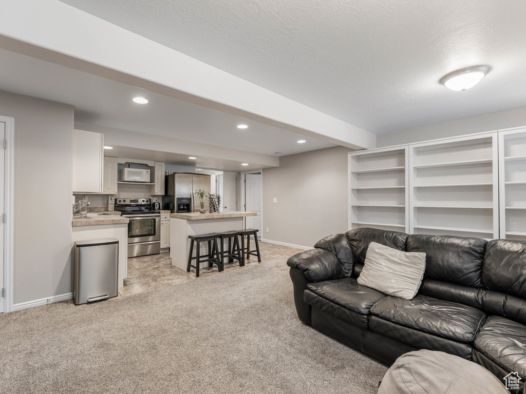 Living area with light colored carpet, recessed lighting, baseboards, and a textured ceiling