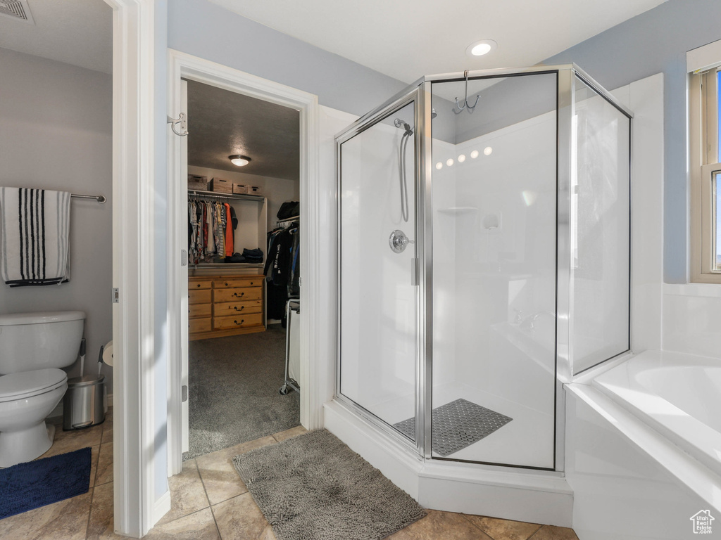 Bathroom featuring a stall shower, a bath, toilet, and a walk in closet