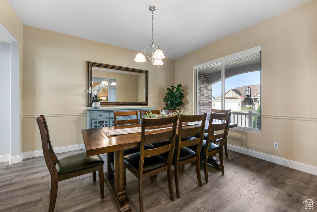 Dining area with a chandelier, wood finished floors, and baseboards
