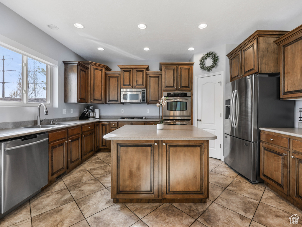Kitchen with stainless steel appliances, a sink, a kitchen island, recessed lighting, and light countertops