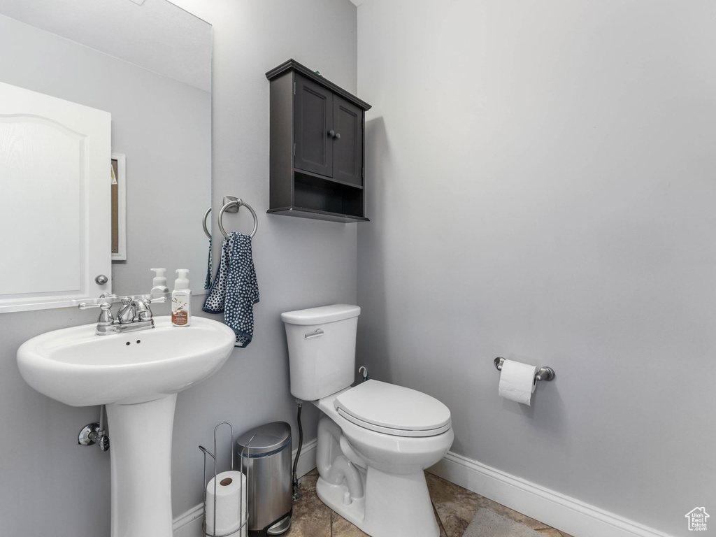 Half bath with baseboards, toilet, and a sink
