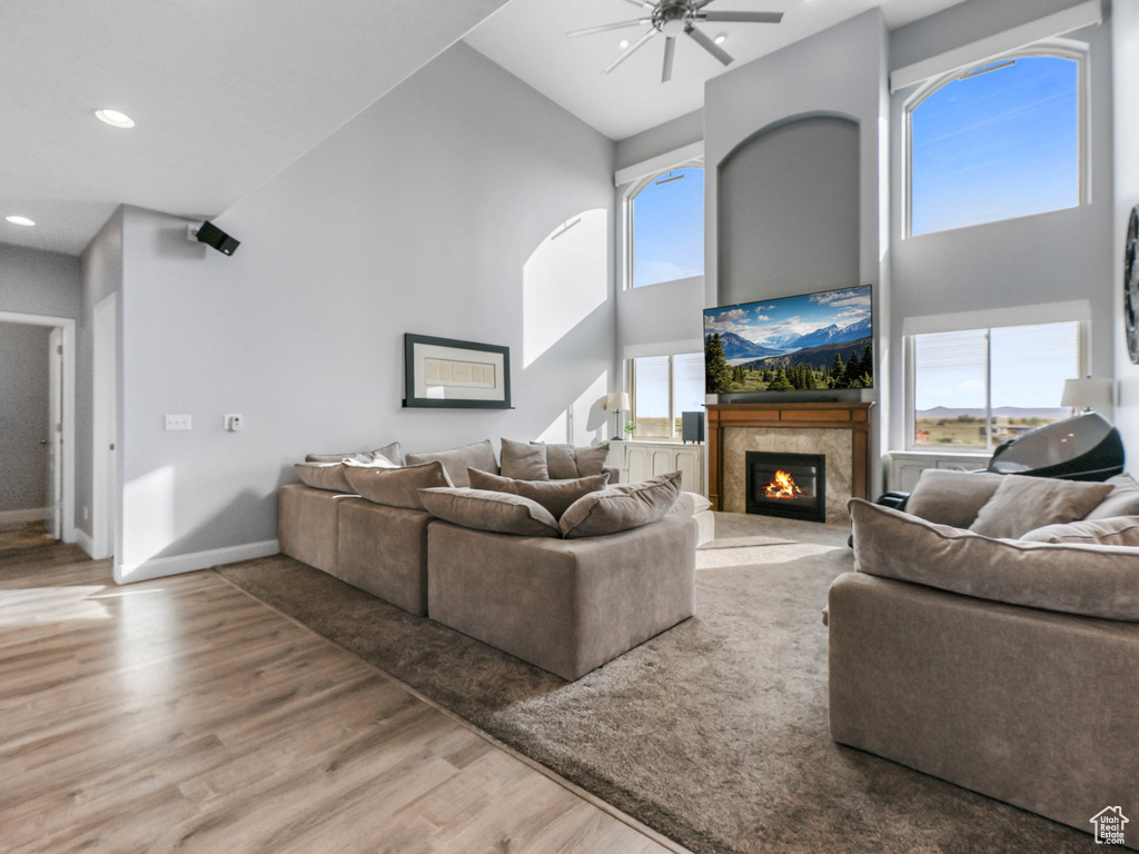 Living area featuring high vaulted ceiling, ceiling fan, wood finished floors, a premium fireplace, and baseboards