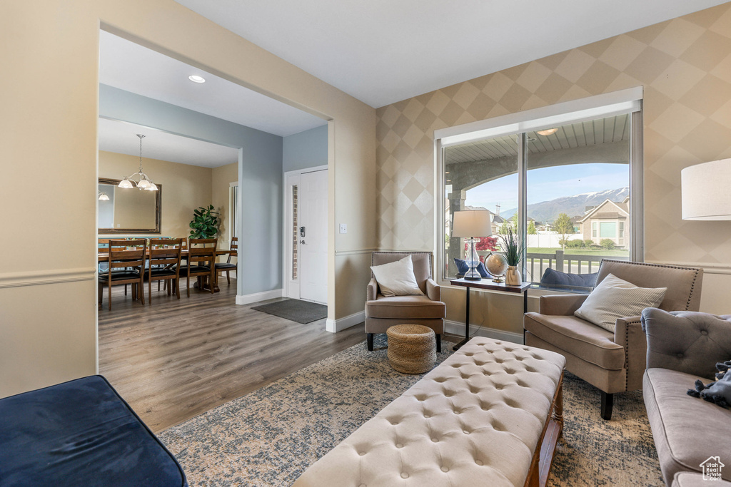 Living area with wallpapered walls, wood finished floors, baseboards, and a chandelier