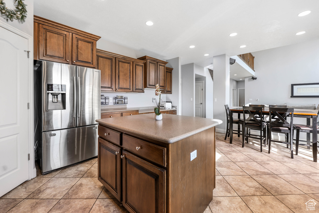 Kitchen with stainless steel fridge with ice dispenser, light tile patterned flooring, a center island, recessed lighting, and light countertops