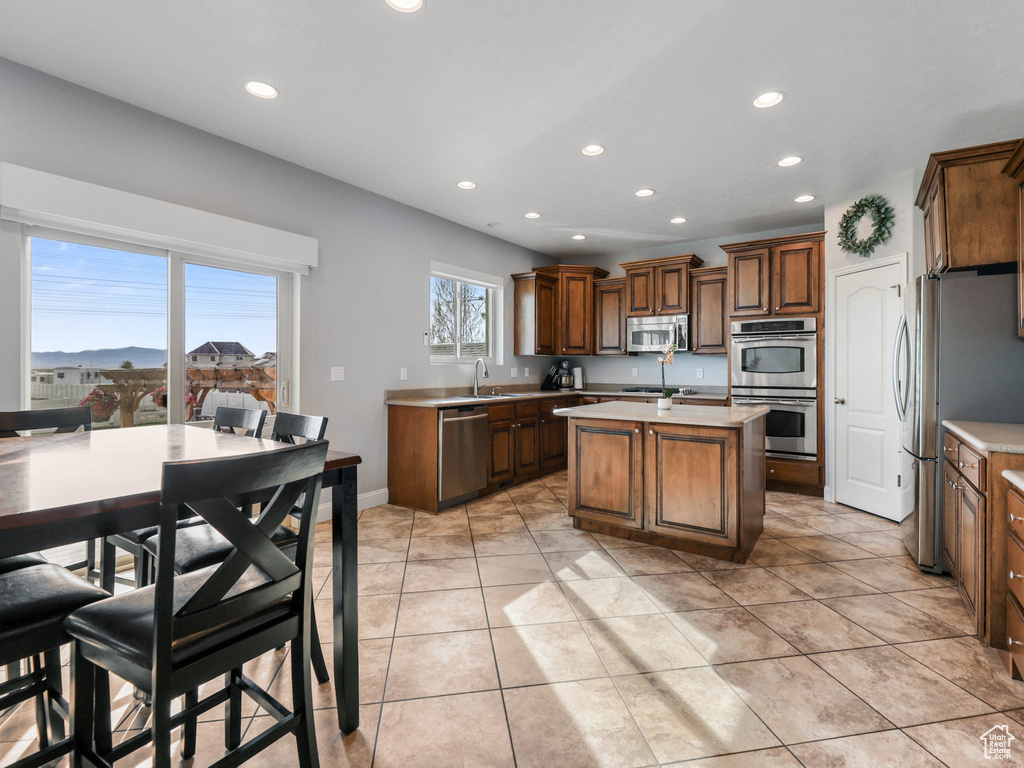 Kitchen featuring stainless steel appliances, recessed lighting, a sink, light countertops, and a center island