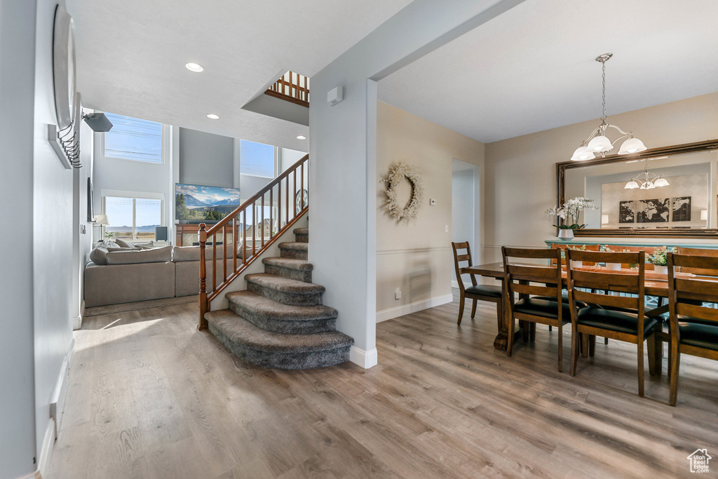 Dining area with wood finished floors, stairs, a chandelier, and baseboards