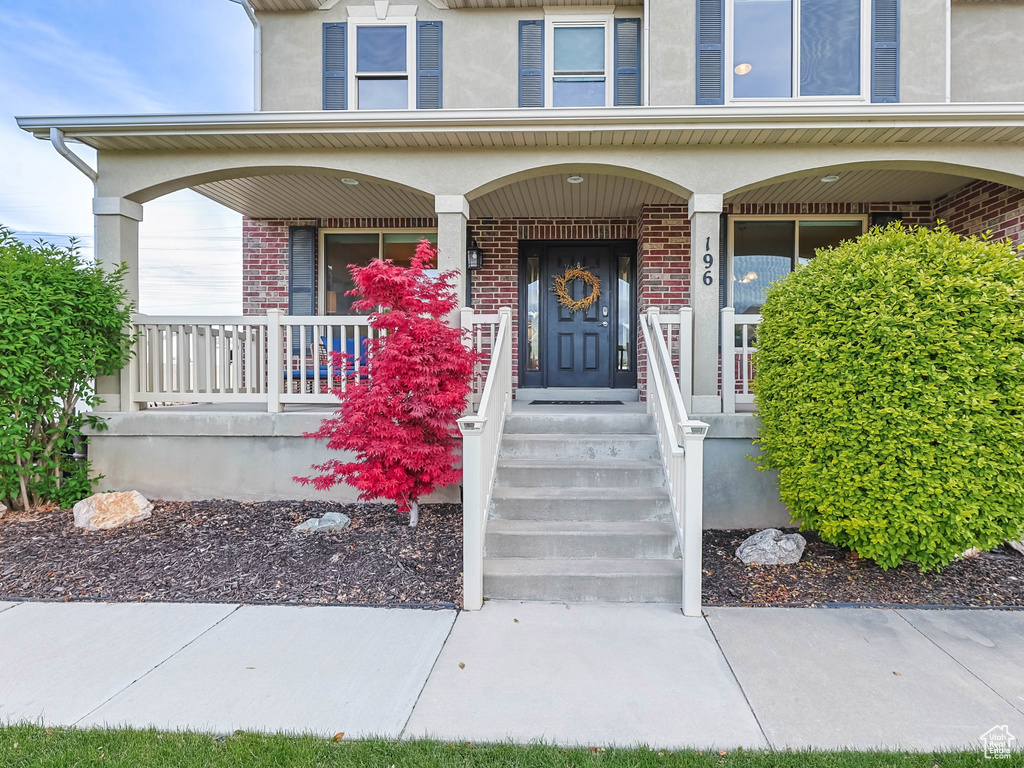 Entrance to property featuring covered porch and brick siding