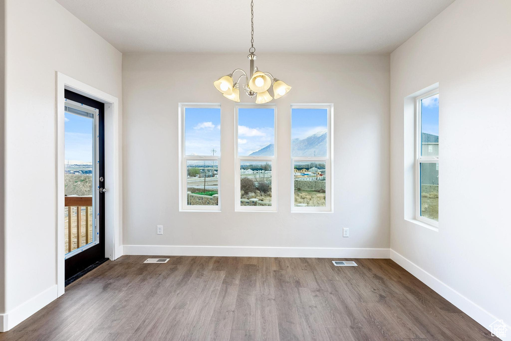 Unfurnished dining area with a chandelier, dark wood-style floors, and baseboards