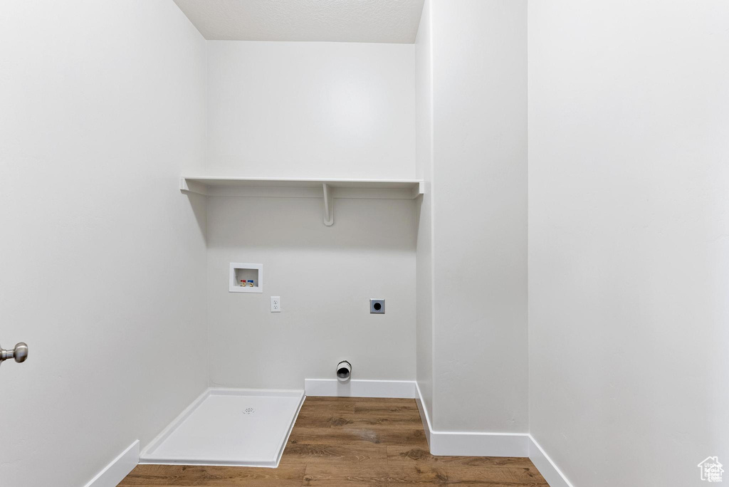 Washroom with hookup for a washing machine, electric dryer hookup, wood finished floors, and baseboards