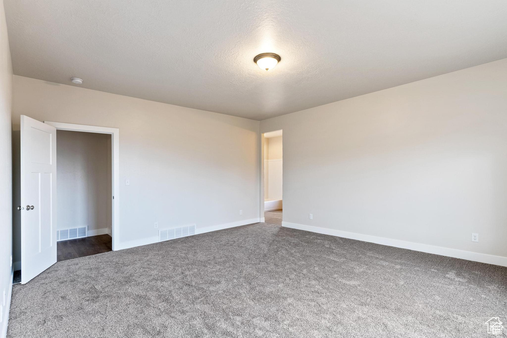Spare room with carpet, baseboards, and a textured ceiling