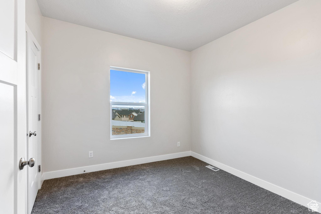 Empty room featuring dark carpet and baseboards