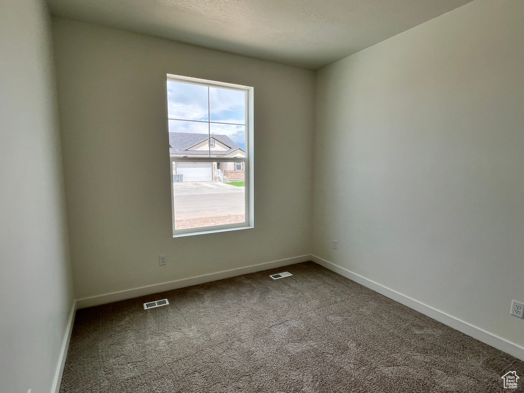 Empty room with dark carpet and baseboards