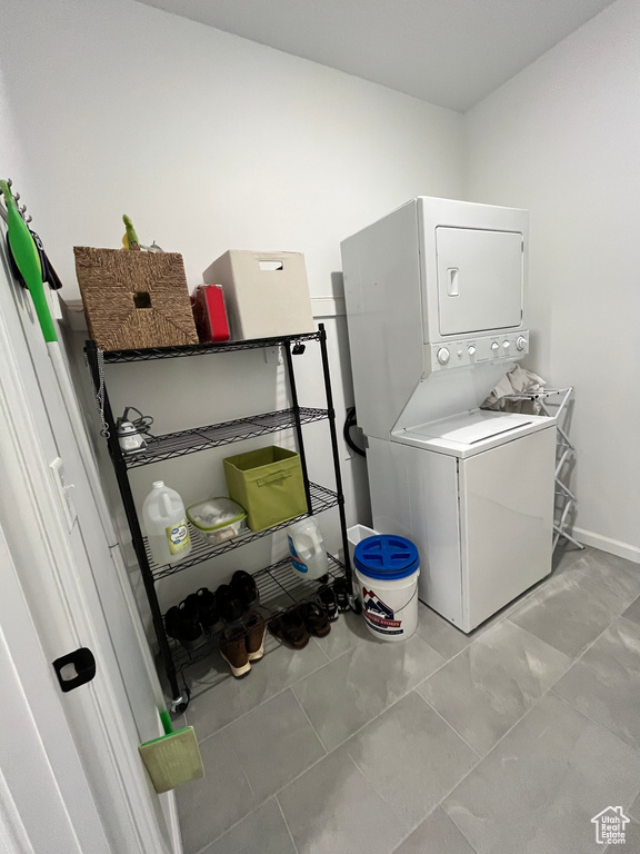 Laundry room featuring stacked washer and clothes dryer and baseboards