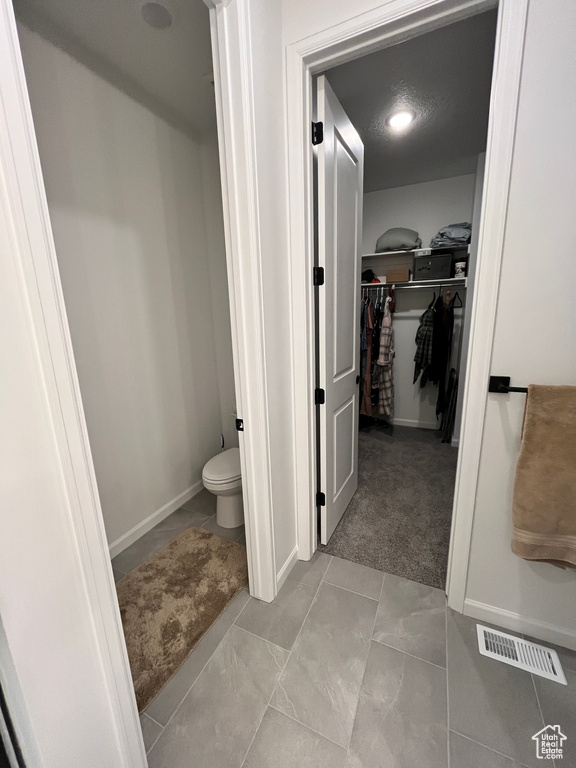 Bathroom featuring a walk in closet, toilet, and baseboards