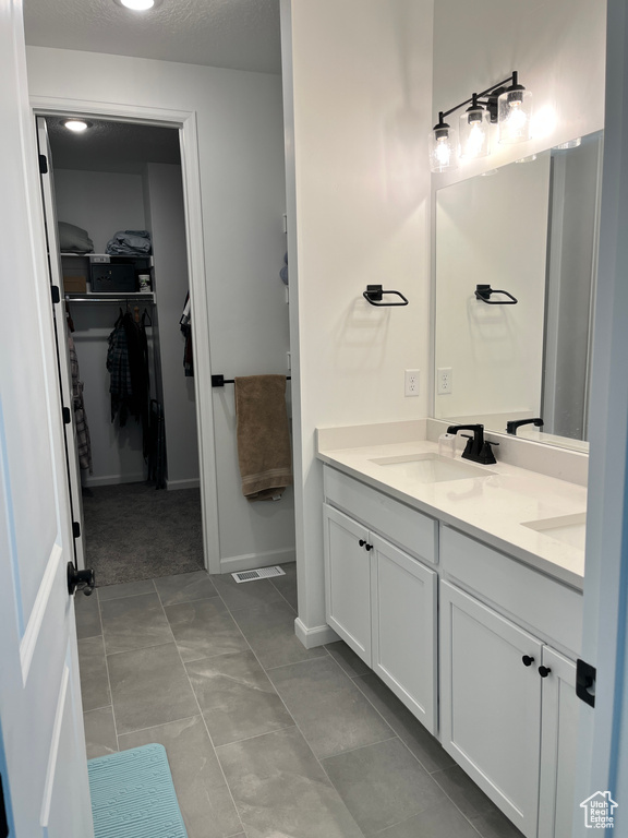 Full bathroom with double vanity, a walk in closet, and baseboards