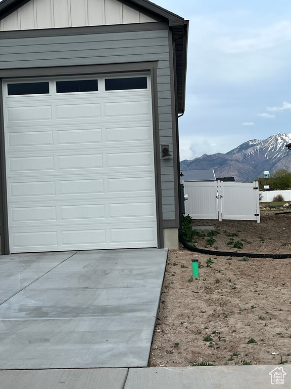 Garage featuring a mountain view, driveway, and fence
