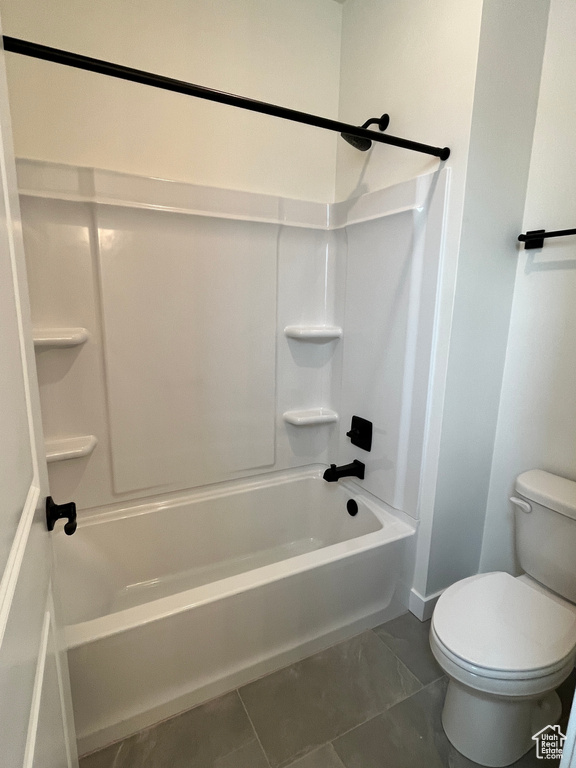 Bathroom with toilet,  shower combination, and baseboards