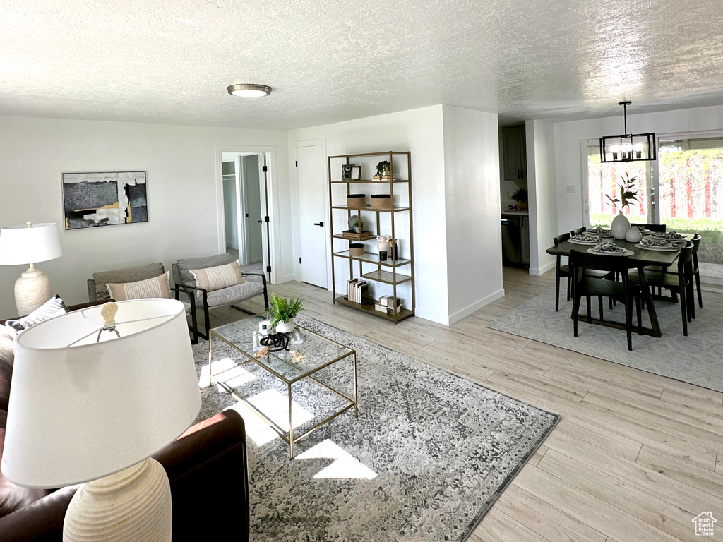 Living area featuring a textured ceiling, wood finished floors, a chandelier, and baseboards