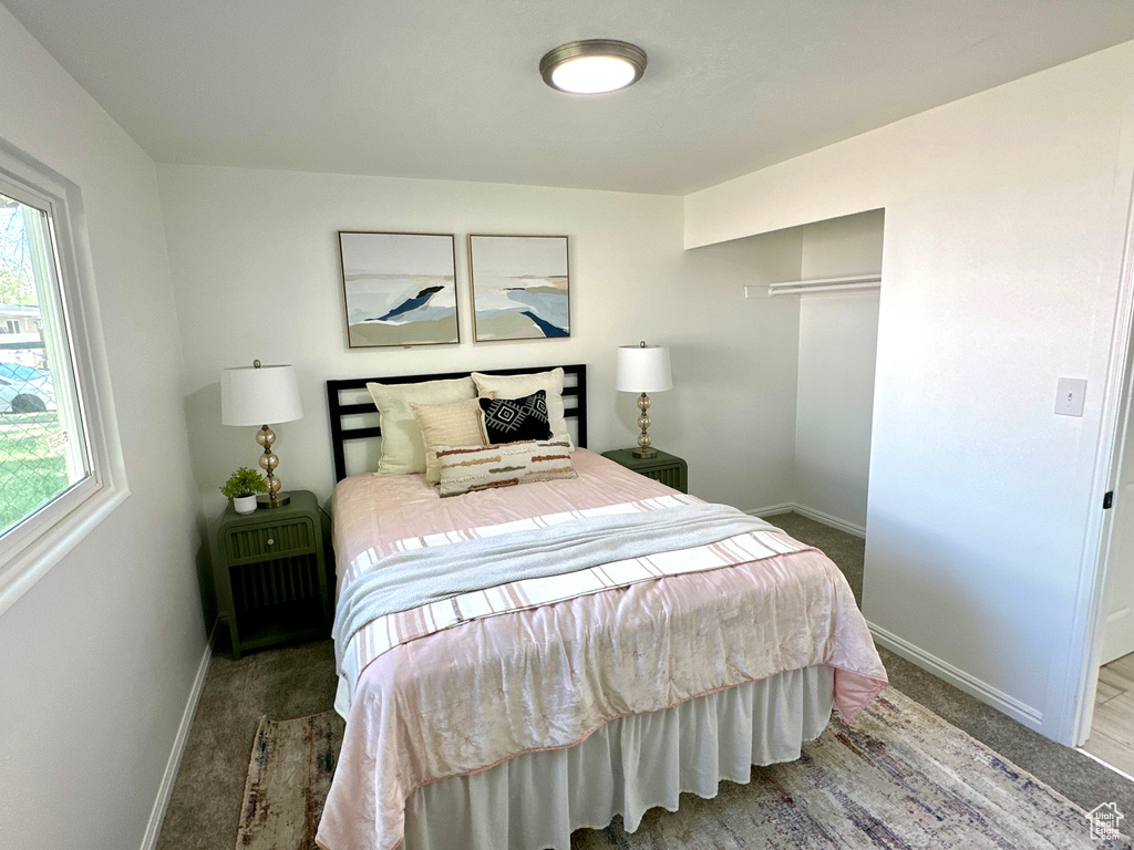 Carpeted bedroom featuring multiple windows, baseboards, and a closet