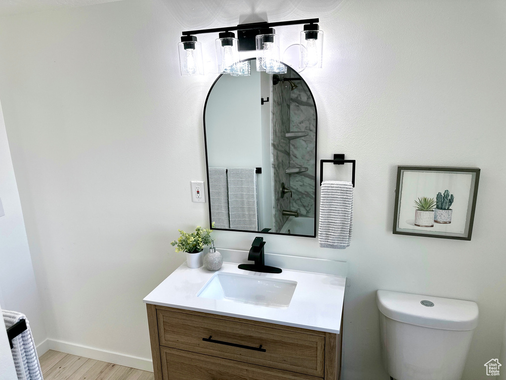Bathroom with vanity, toilet, wood finished floors, and baseboards