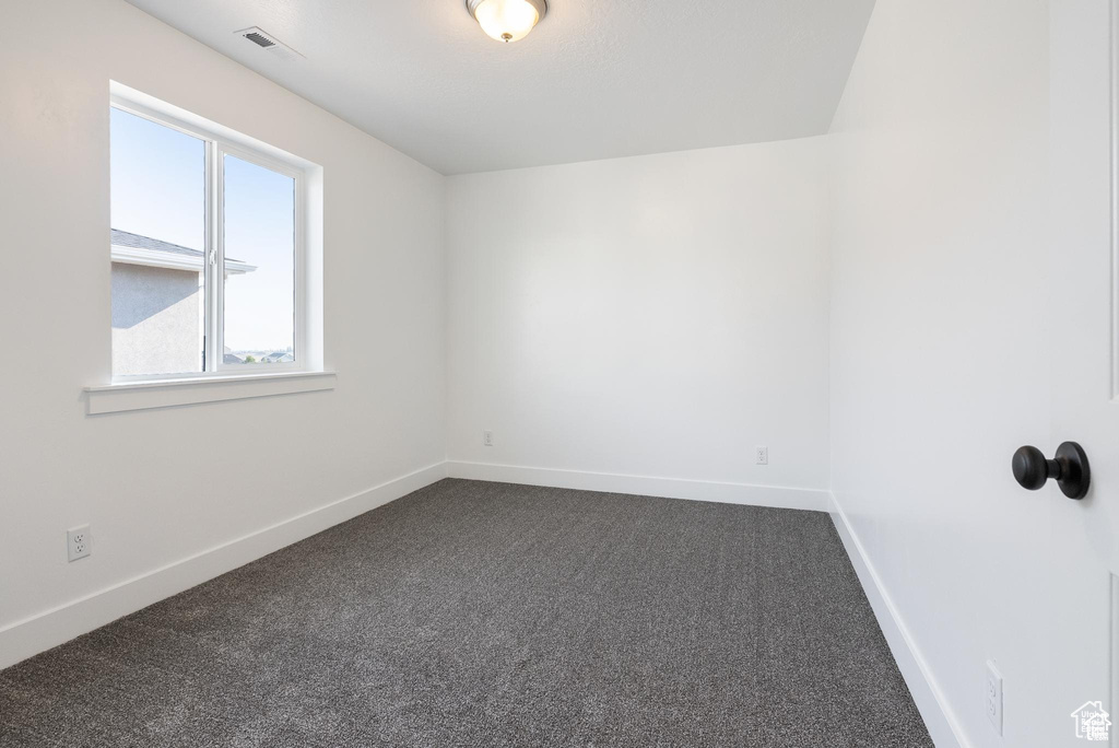 Empty room with dark colored carpet and baseboards