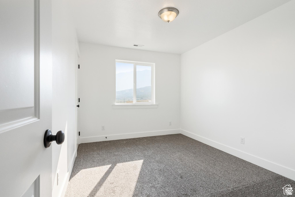 Empty room featuring dark colored carpet and baseboards
