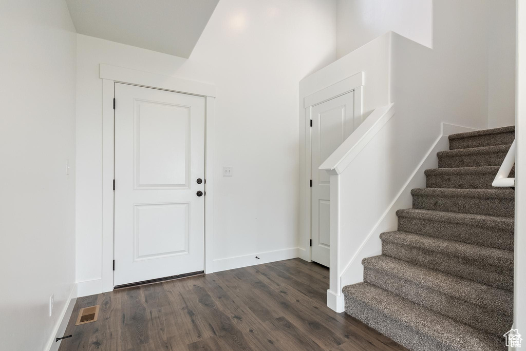 Entrance foyer featuring dark wood-style flooring, stairway, and baseboards