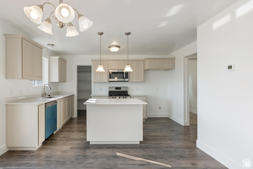 Kitchen with appliances with stainless steel finishes, a sink, baseboards, a chandelier, and dark wood-type flooring