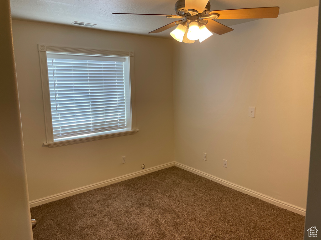 Unfurnished room with dark carpet, a ceiling fan, and baseboards
