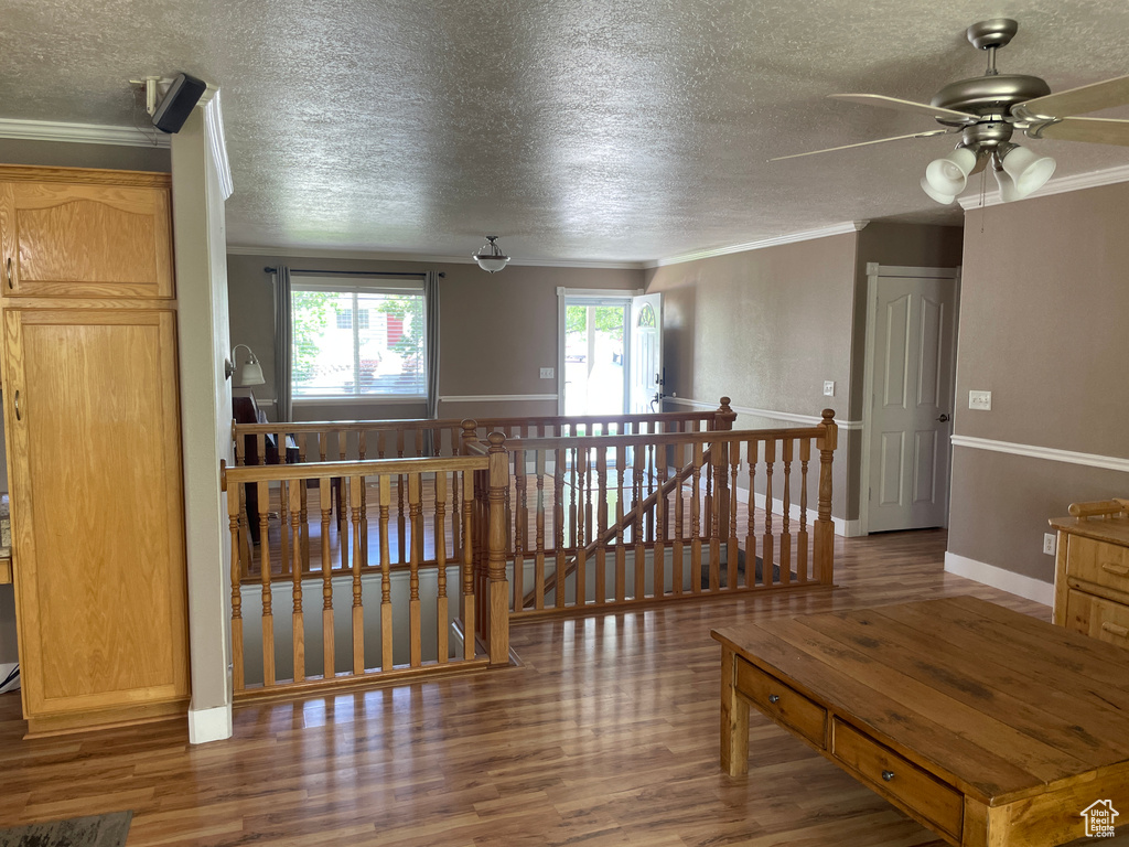 Interior space featuring an upstairs landing, a textured ceiling, wood finished floors, and ornamental molding