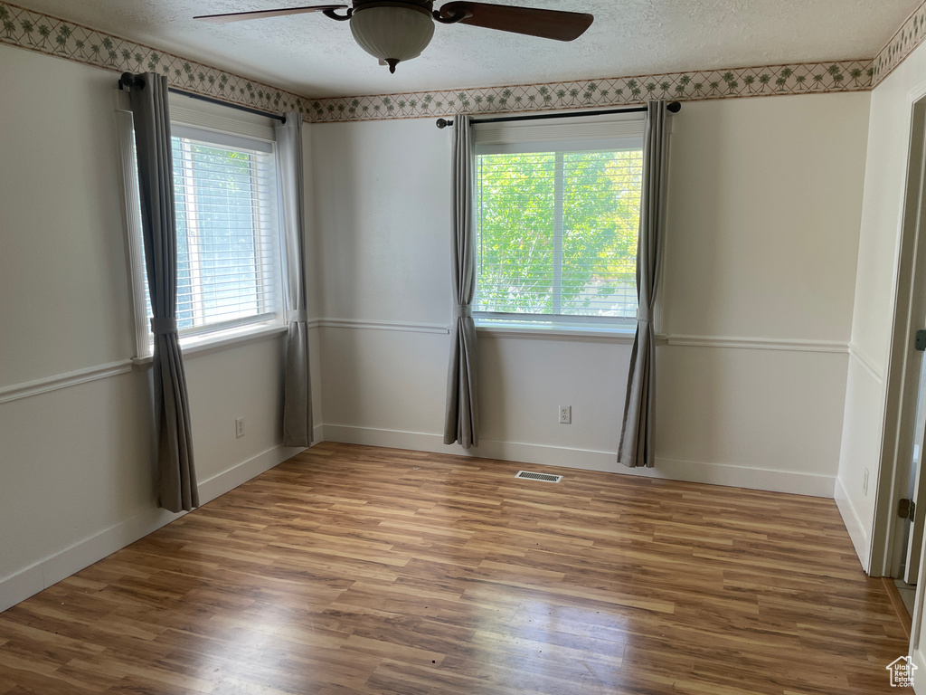 Unfurnished bedroom with a textured ceiling, wood finished floors, baseboards, and a ceiling fan