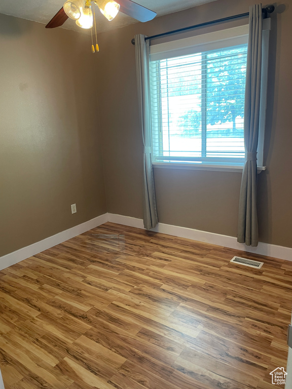 Spare room featuring ceiling fan, baseboards, and wood finished floors