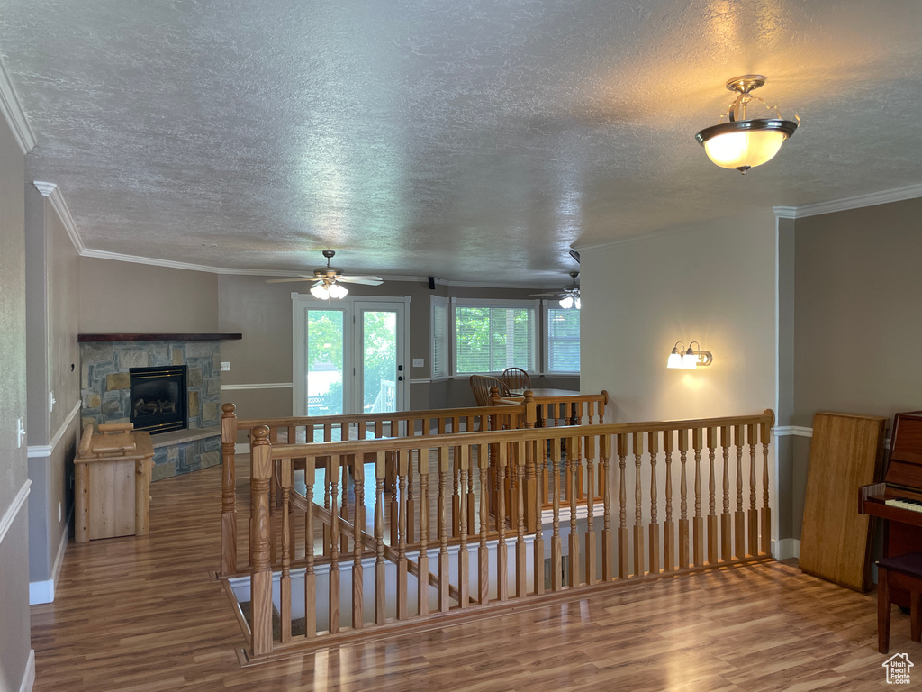 Living area featuring wood finished floors, a textured ceiling, a ceiling fan, baseboards, and a fireplace