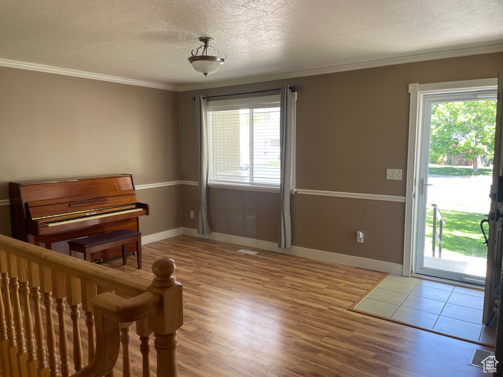 Interior space with multiple windows, a textured ceiling, ornamental molding, access to outside, and wood finished floors