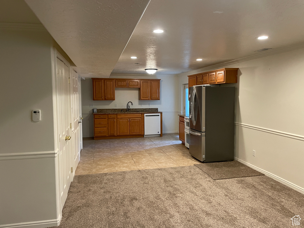Kitchen featuring freestanding refrigerator, white dishwasher, light carpet, recessed lighting, and a sink