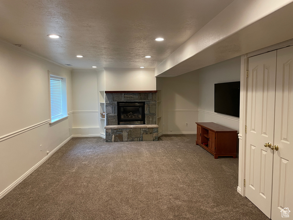 Unfurnished living room featuring carpet flooring, a stone fireplace, recessed lighting, baseboards, and a textured ceiling