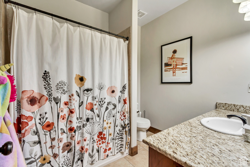 Full bathroom featuring tile patterned floors, toilet, vanity, and a shower with curtain