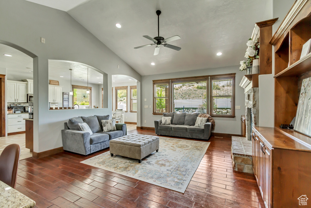 Living area featuring a ceiling fan, arched walkways, dark wood finished floors, baseboards, and recessed lighting