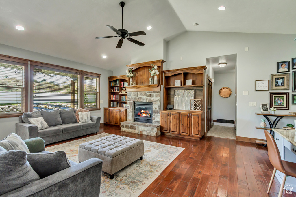 Living room featuring ceiling fan, a fireplace, baseboards, dark wood-style flooring, and high vaulted ceiling
