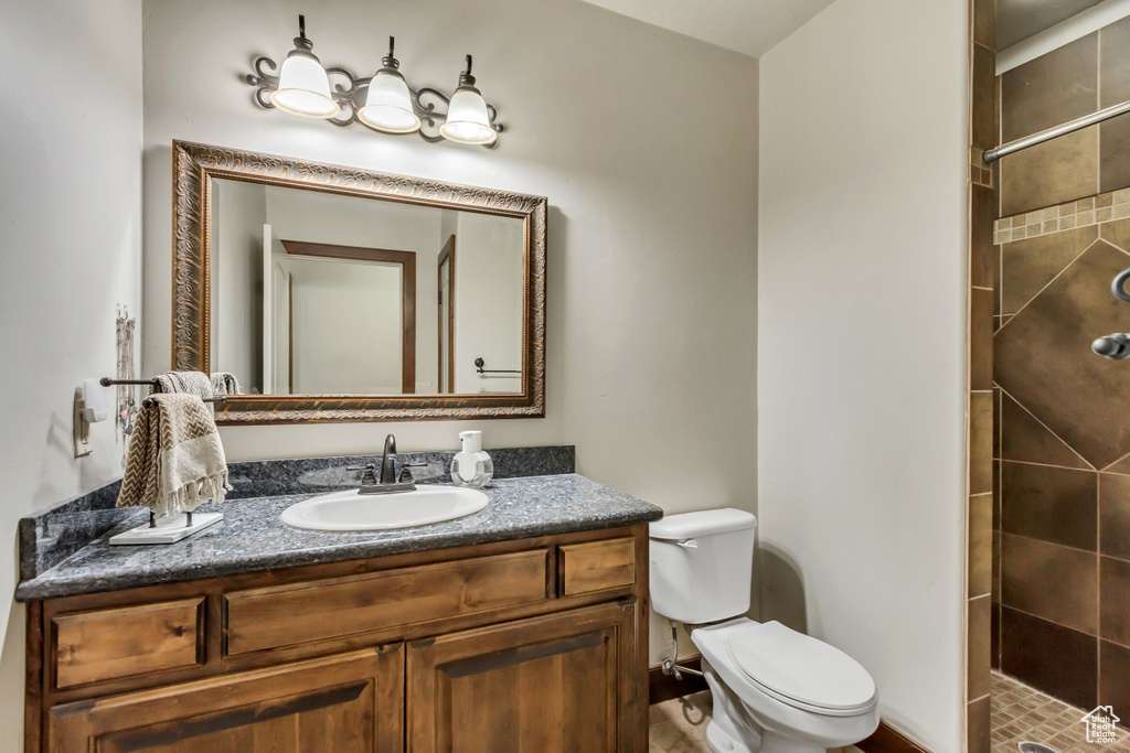 Full bath featuring toilet, a tile shower, and vanity