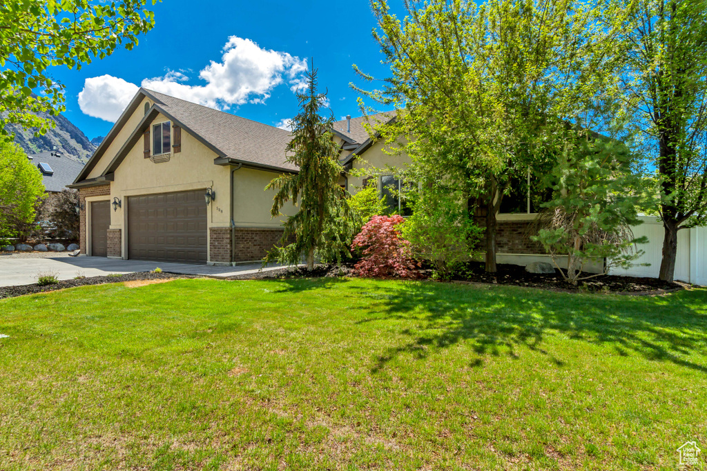 View of front of property with stucco siding, concrete driveway, brick siding, and roof with shingles