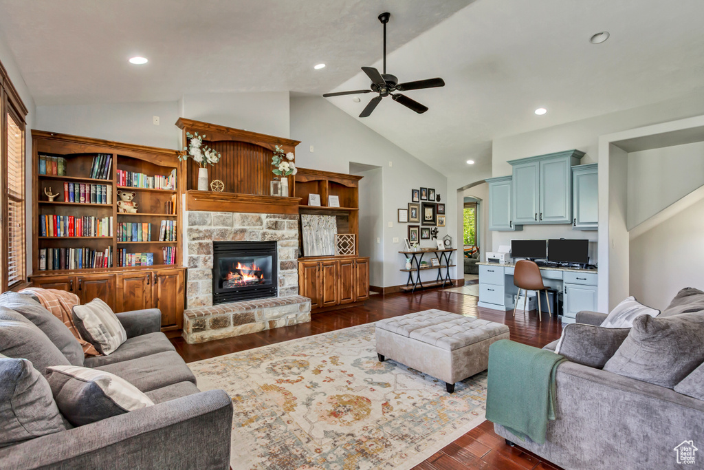 Living room featuring ceiling fan, dark wood-type flooring, a stone fireplace, arched walkways, and recessed lighting