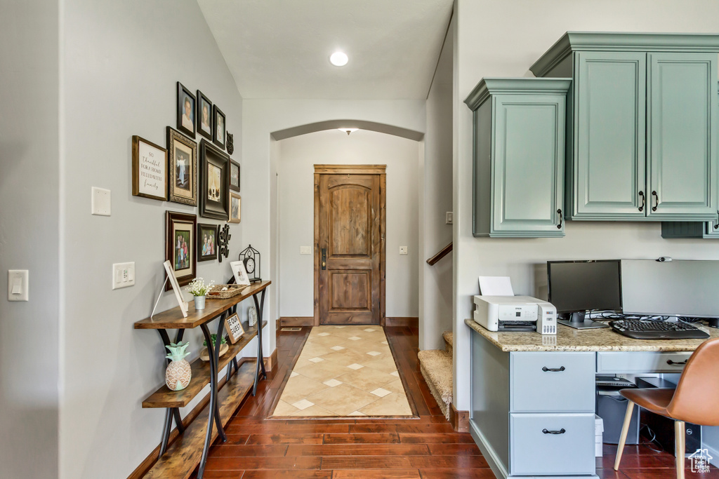 Home office featuring arched walkways, dark wood-style flooring, baseboards, and built in study area