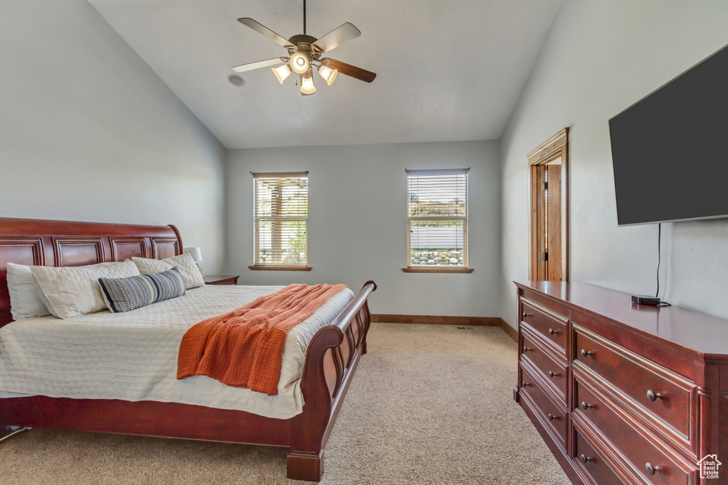 Bedroom with lofted ceiling, light carpet, baseboards, and ceiling fan